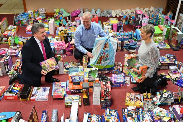 Photo of Amanda Stewart, Probation Chief Executive, and Prisons Director General, Ronnie Armour with Robin Scott, Chief Executive of the Prison Fellowship NI, among the all the gifts donated by their staff to the Fellowship’s Christmas Hope 